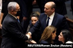 Benjamin Netanyahu (L) greets new Israel Prime minister Naftali Bennett following the vote on the new coalition at the Knesset, Israel's parliament, in Jerusalem June 13, 2021. (REUTERS/Ronen Zvulun)