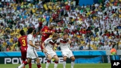 Ghana's Andre Ayew heads the ball over Germany's Per Mertesacker, center, and Germany's Shkodran Mustafi, right, to score his sides' first goal during the group G World Cup soccer match between Germany and Ghana at the Arena Castelao in Fortaleza, Brazil,