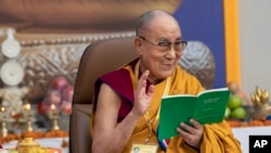 FILE - Tibetan spiritual leader the Dalai Lama smiles as he reads from a book during an event at the Kirti Monastery in Dharmsala, India, Dec. 7, 2019. (AP Photo/Ashwini Bhatia)