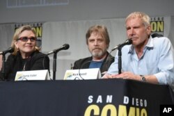 FILE - Carrie Fisher, Mark Hamill, and Harrison Ford attend Lucasfilm's "Star Wars: The Force Awakens" panel on day 2 of Comic-Con International in San Diego, Calif., July 10, 2015.