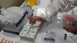 FILE - A medical worker prepares vials of the COVID-19 vaccines, Chinese Sinopharm, left, Sputnik V, center, and Pfizer at a vaccine center in Belgrade, Serbia, May 6, 2021.