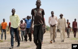 In this photo taken May 2, 2018, men walk over to greet a humanitarian aid team in Kandak, South Sudan.