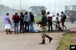 A soldier monitors the removal of a barricade as protestors gather during a demonstration over the hike in fuel prices in Harare, Zimbabwe, Tuesday, Jan. 15, 2019.