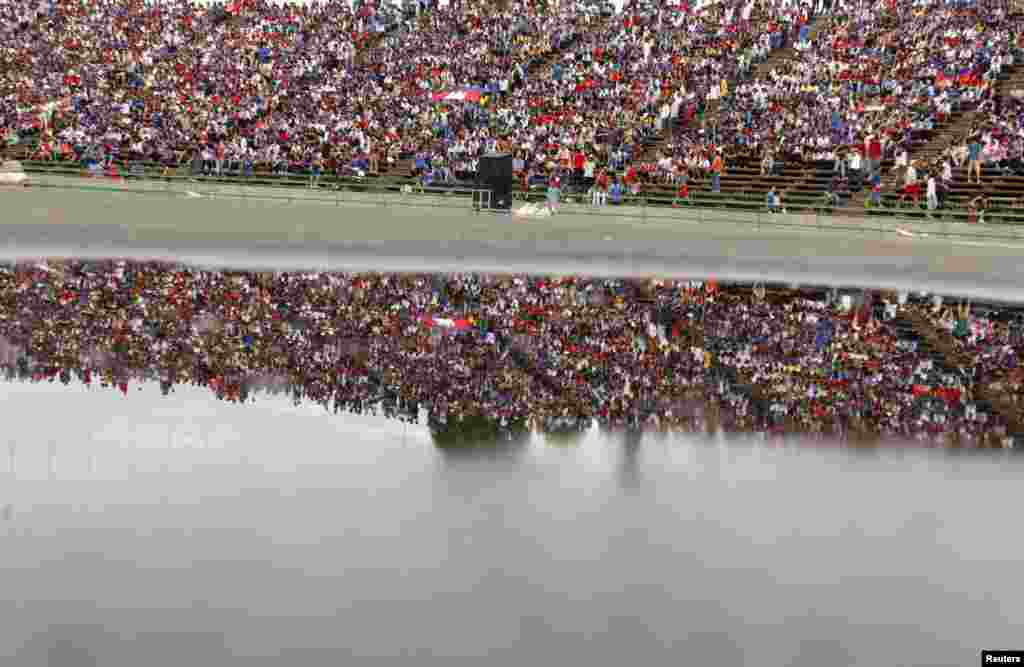 Fans of Cambodia's soccer team are reflected in a puddle of water at a 2018 World Cup qualifying soccer match between Cambodia and Afghanistan at the Olympic Stadium in Phnom Penh.