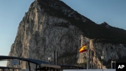 FILE - In this March 1, 2017 photo, a Spanish flag flies on top of the customs house on the Spanish side of the border between Spain and the British overseas territory of Gibraltar with the Rock as a background, in La Linea de la Concepcion, Southern Spai