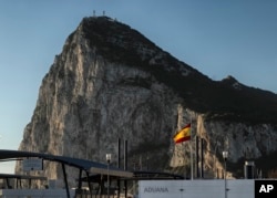 FILE - A Spanish flag flies on top of the customs house on the Spanish side of the border between Spain and the British overseas territory of Gibraltar with the Rock as a background, in La Linea de la Concepcion, southern Spain, March 1, 2017.
