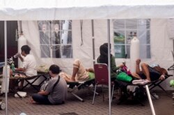 Pasien dirawat di bawah tenda yang didirikan di kompleks rumah sakit untuk menangani masuknya orang yang menderita virus corona, di Yogyakarta pada 13 Juli 2021. (Foto: AFP)