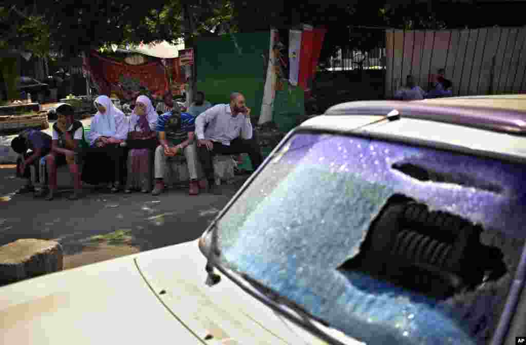 Supporters of Egypt's ousted President Mohamed Morsi sit next to a damaged car during clashes with police near Cairo University in Giza, July 23, 2013. 