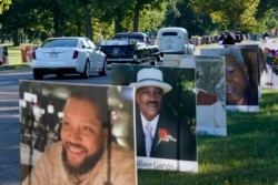 A procession of vehicles drive past photos of Detroit victims of COVID-19, Monday, Aug. 31, 2020 on Belle Isle in Detroit.