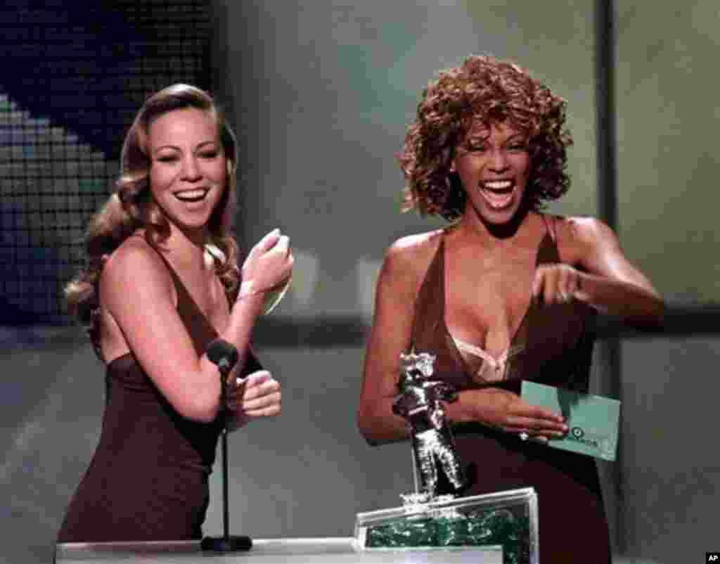 FILE - In this Sept. 10, 1998 file photo, Mariah Carey, left, and Whitney Houston present the award for Best Male Video during the MTV Video Music Awards, in Universal City, Calif. Whitney Houston, who reigned as pop music's queen until her majestic voice