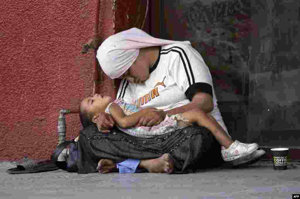 Seorang perempuan pengungsi Suriah memangku anaknya saat mereka tertidur di trotoar di kota Sidon, Lebanon selatan.