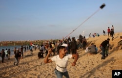 Protesters gather while others hurl stones at Israeli troops near the fence of the Gaza Strip border with Israel during a protest on the beach near Beit Lahiya, northern Gaza Strip, Nov. 19, 2018.