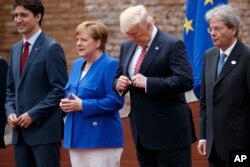 President Donald Trump adjusts his jacket during a family photo with G7 leaders at the Ancient Greek Theater of Taormina, Friday, May 26, 2017, in Taormina, Italy.