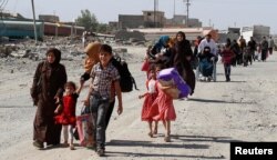 FILE - Residents who fled their homes due to fighting between Iraqi forces and Islamic State militants return to their village cleared by the Iraqi forces in western Mosul in Iraq, June 7, 2017.