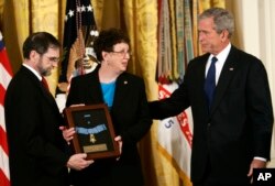 FILE - Then-President Bush, right, presents the Medal of Honor to parents of Army Pfc. Ross McGinnis, of Knox, Pennsylvania, in the East Room of the White House in Washington, June 2, 2008.