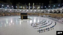 A picture taken June 23, 2020 shows a few worshippers performing al-Fajr prayer at the Kaaba, Islam's holiest shrine, at the Grand Mosque complex in Saudi Arabia's holy city of Mecca. (Photo by STR / AFP)