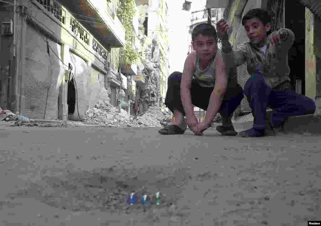 Children play with marbles in a street in the besieged area of Homs, Syria, May 30, 2013. 