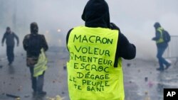 Göstericinin sarı yeleğinin arkasında, ''Macron, hırsız, yalancı, düzenbaz, defol git, halk seni istemiyor'' yazıyor