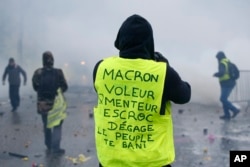 A demonstrator wearing a yellow jacket reading "Macron, thief, lier, crook, go away, the people banishes you" near the Champs-Elysees avenue during a demonstration Dec.1, 2018 in Paris.