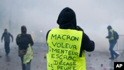 A demonstrator wearing a yellow jacket reading "Macron, thief, lier, crook, go away, the people banishes you" near the Champs-Elysees avenue during a demonstration Saturday, Dec.1, 2018 in Paris. 