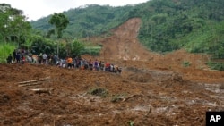 Villagers and rescuers examine the site where a landslide swept away houses in Jemblung village, Central Java, Indonesia, Dec. 13, 2014.