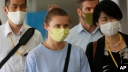 Belarusian Olympic sprinter Krystsina Tsimanouskaya, center, arrives at Narita International Airport in Narita, east of Tokyo Wednesday, Aug. 4, 2021. (AP Photo/Koji Sasahara)