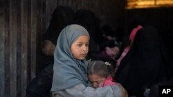 Children ride in the back of a truck that is part of a convoy evacuating hundreds out of the last territory held by Islamic State militants, in Baghouz, eastern Syria, Feb. 20, 2019.