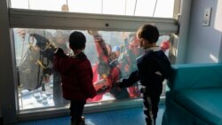 Para pemain akrobat tampil dengan kostum superhero menyapa anak-anak yang tengah menunggu di ruangan khusus perawatan untuk anak di Rumah Sakit San Paolo di Milan, Italia, pada 15 desember 2021. (Foto: AP/Luca Bruno)