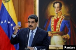 FILE - Venezuela's President Nicolas Maduro holds a copy of the National Constitution while he speaks during a news conference at Miraflores Palace in Caracas, Venezuela, Jan. 9, 2019.