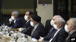 In this photo released by the official website of the Office of the Iranian Presidency, cabinet members wearing face masks and gloves attend their meeting in Tehran, Iran, Wednesday, March 18, 2020. 