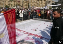 Mourners throw roses and pray over the names of some of those killed in Egypt's revolution, at a makeshift memorial in Tahrir Square, Cairo, February 12, 2011