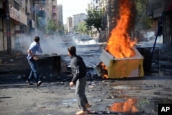 FILE - With tanks in the background, youths set fire to barricades in Diyarbakir, Turkey, hours after Kurds protesting the Islamic State advance on Kobani, Syria, had clashed with police, Oct. 8, 2014.