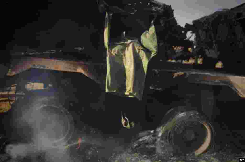 A soldiers jacket belonging to forces of Moammar Gadhafi is displayed on a still burning tank on the outskirts of Benghazi, eastern Libya, Sunday, March 20, 2011. The U.S. military said 112 Tomahawk cruise missiles were fired from American and British shi