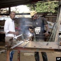 Elhadji Moctar Gueye stands beside one of his employees at his metallic workshop in Dakar, December 19, 2011.