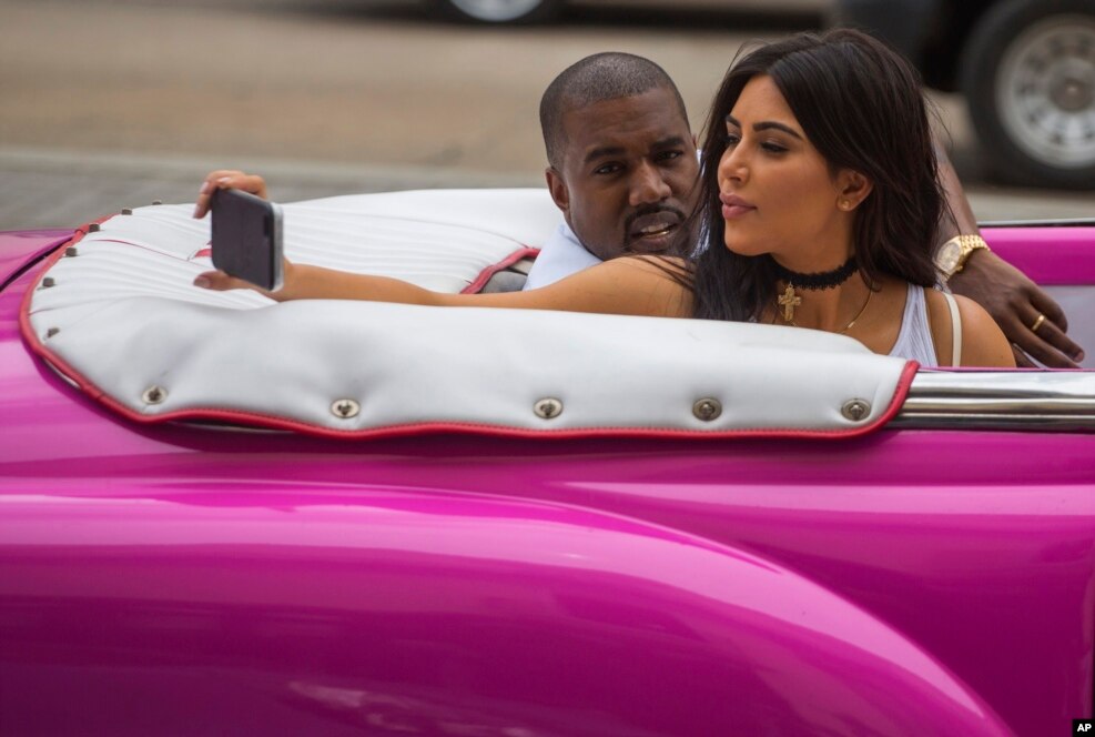 American reality-show star Kim Kardashian takes a selfie as she rides on a classic car next to her husband, rap singer Kanye West in Havana, Cuba on May 4, 2016.