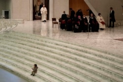 Pope Francis arrives for his weekly general audience as a child plays on the steps of the Paul VI Hall, at the Vatican, Wednesday, Dec. 22, 2