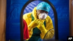 In this Thursday, Oct. 16, 2014 file photo, a healthcare worker dons in protective gear before entering an Ebola treatment center in the west of Freetown, Sierra Leone. (AP Photo/Michael Duff, File)