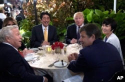FILE - President Donald Trump, third from right, and first lady Melania Trump, hidden at left, sit down to dinner with Japanese Prime Minister Shinzo Abe, third from left, and his wife Akie Abe, right, at Mar-a-Lago in Palm Beach, Florida, Feb. 10, 2017.