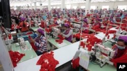 FILE PHOTO - Garment workers sew clothes in a factory as they wait for a visit by Prime Minister Hun Sen outside of Phnom Penh, Cambodia, Wednesday, Aug. 30, 2017. 