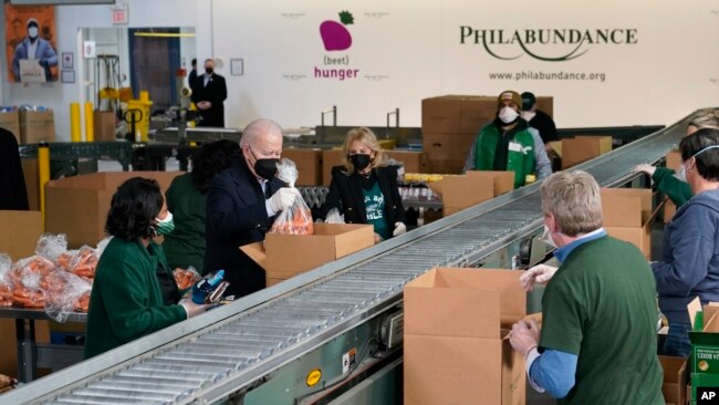 President Joe Biden and first lady Jill Biden pack produce while volunteering at hunger relief organization Philabundance, in Philadelphia, Pennsylvania, Jan. 16, 2022.