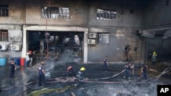 Firemen work to put the fire under control at a still-smoldering Kentex rubber slipper factory in Valenzuela city, a northern suburb of Manila, Philippines, Wednesday, May 13, 2015. 