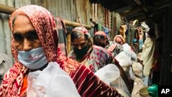 বাংলাদেশের রাজধানী ঢাকায় কয়েকজন মহিলা মিশন সেভ বাংলাদেশ কর্তৃক বিতরণকৃত খাবারের প্যাকেট সংগ্রহ করে ঘরে ফিরেছেন। (ফাইল ছবি) 