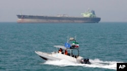 FILE-- In this July 2, 2012 file photo, an Iranian Revolutionary Guard speedboat moves in the Persian Gulf while an oil tanker is seen in background.
