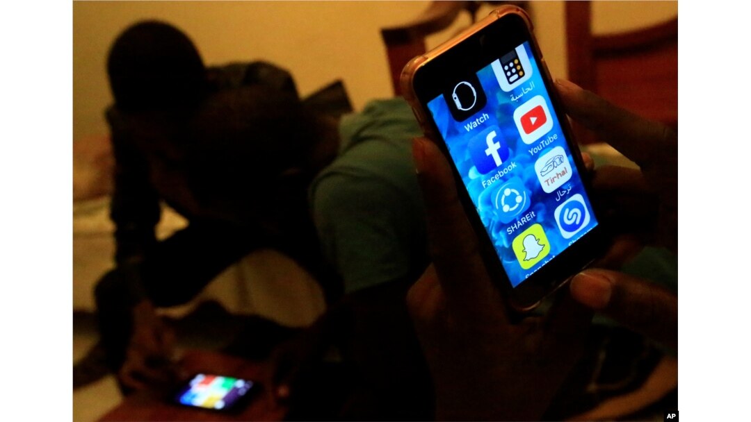 A Sudanese man holds his phone with restricted internet access to social media platforms, in Khartoum, Jan. 1, 2019.