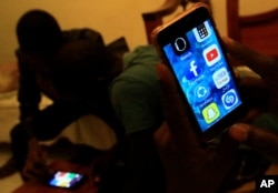 A Sudanese man holds his phone with restricted internet access to social media platforms, in Khartoum, Jan. 1, 2019.