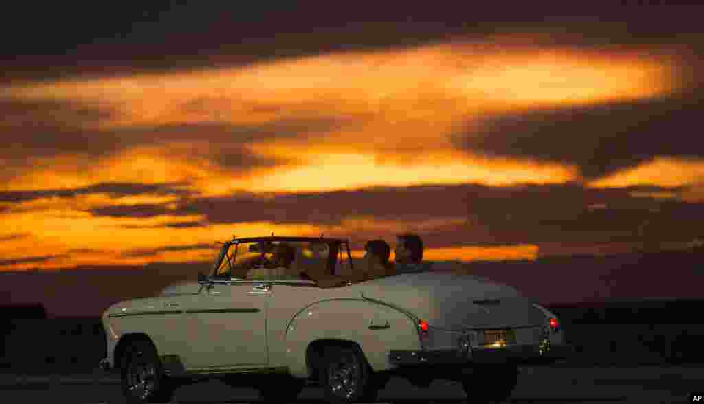 Tourists ride a vintage American convertible during sunset on the Malecon in Havana, Cuba, Sept. 30, 2015.