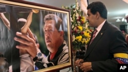 Venezuela's acting President Nicolas Maduro stands in front of a portrait of Venezuela's late President Hugo Chavez after a symbolic swearing in ceremony, March 8, 2013.