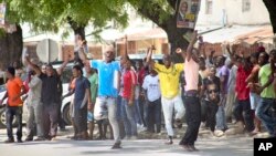 In this photo taken Monday, Oct. 26th, 2015 and made available Wednesday, Oct. 28th, 2015, youths supporting the opposition party dance and chant, predicting a win for their candidate, outside the Electoral Commission office in Stone Town, Zanzibar.