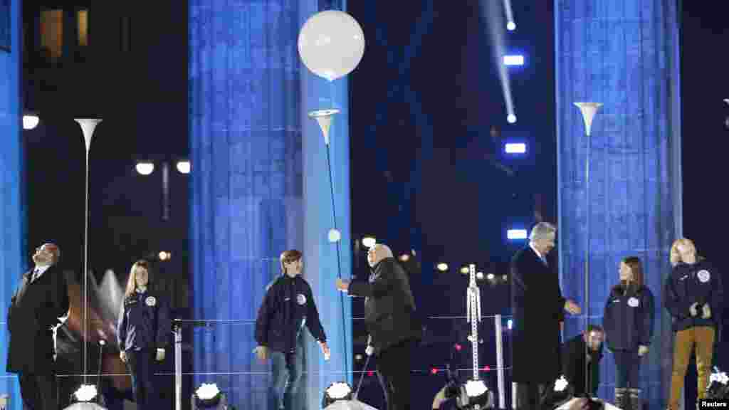 Rais wa zamani wa Urusi Mikhail Gorbachev, (kati kati, akiachilia kibofu chake kutoka eneo maalum laq "Lichtgrenze" (Mpaka wa Taa) mbele ya mlango wa Brandenburg Gate mjini Berlin, Nov. 9, 2014. 