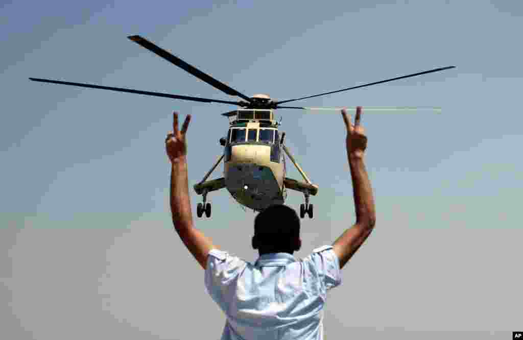 A man flashes victory signs at a military helicopter near the presidential palace in Cairo, July 26, 2013. 
